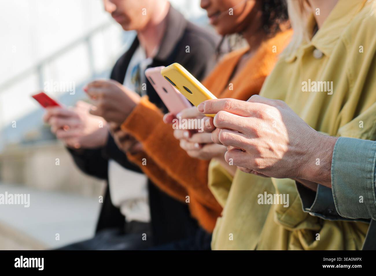Eine Gruppe verschiedener Personen, die sich intensiv mit ihren Smartphones beschäftigen und moderne Technologie und soziale Interaktion in einer entspannten Umgebung unter ihnen präsentieren Stockfoto