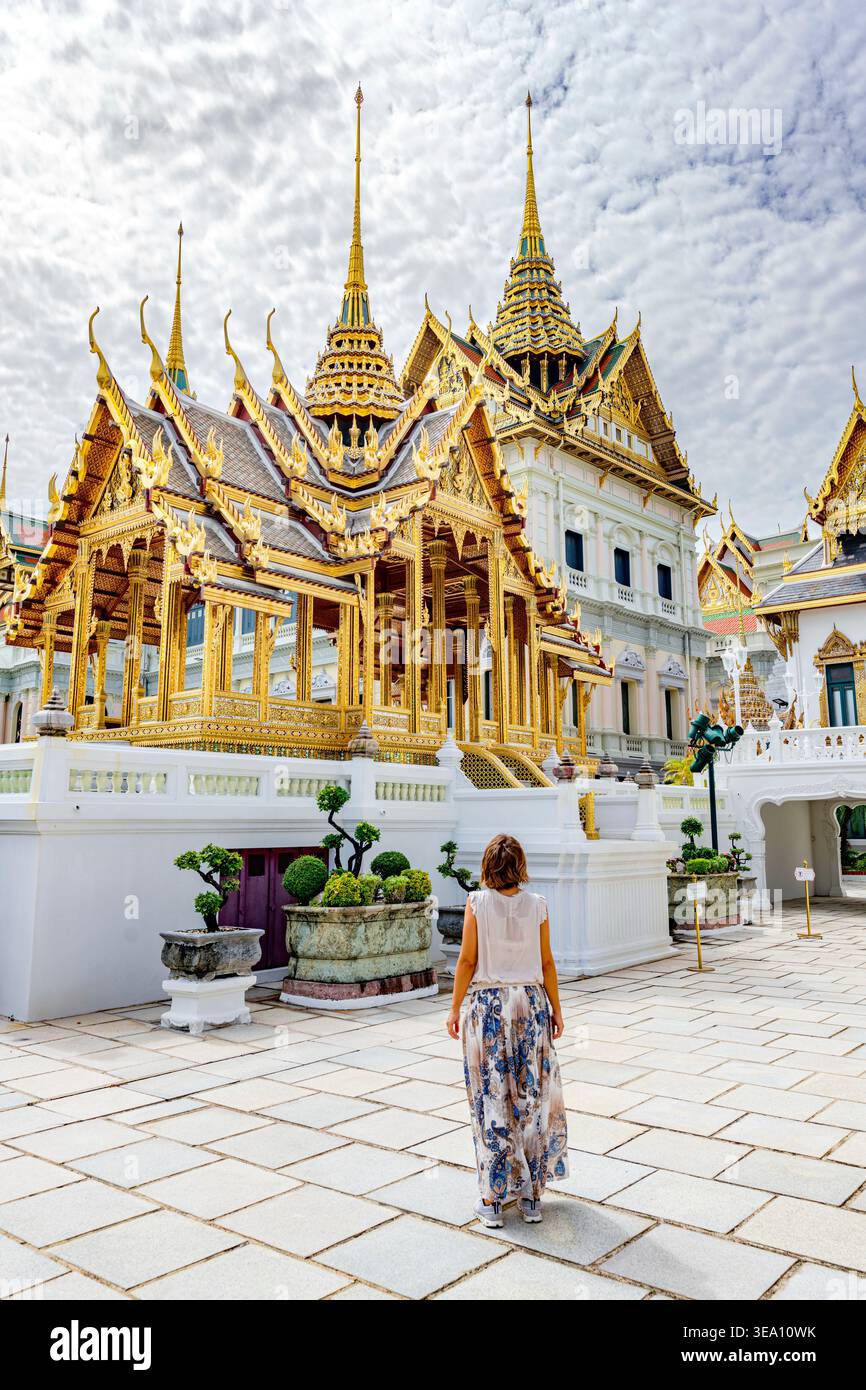 Charmante Frau mit Blick auf die goldene Stupa und Pagoden, Grand Palace, Bangkok, Thailand Stockfoto