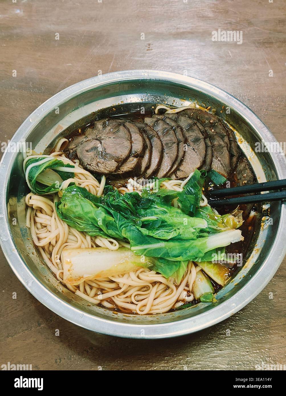 Chinesische Rindfleisch-Nudelsuppe mit Bok Choy in Metallschüssel, Si Chuan-Gerichte im Stil von oben - Smartphone-aufgenommenes Stockfoto