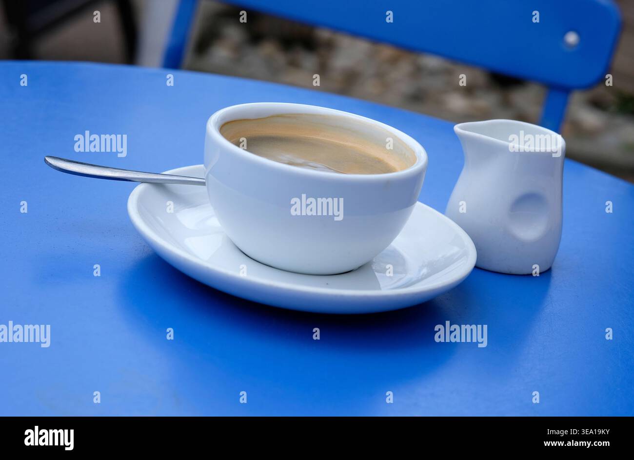 Weiße Kaffeetasse und Untertasse auf blauer Tischplatte Stockfoto