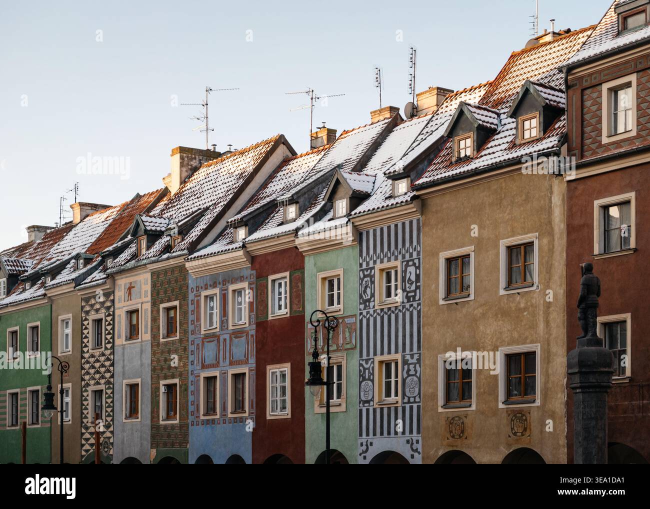 Alte Häuser auf dem Marktplatz in Posen. Reihe farbenfroher traditioneller Häuser auf dem Alten Marktplatz von Posen mit verzierten Fassaden und schneebedeckten Dächern. Stockfoto