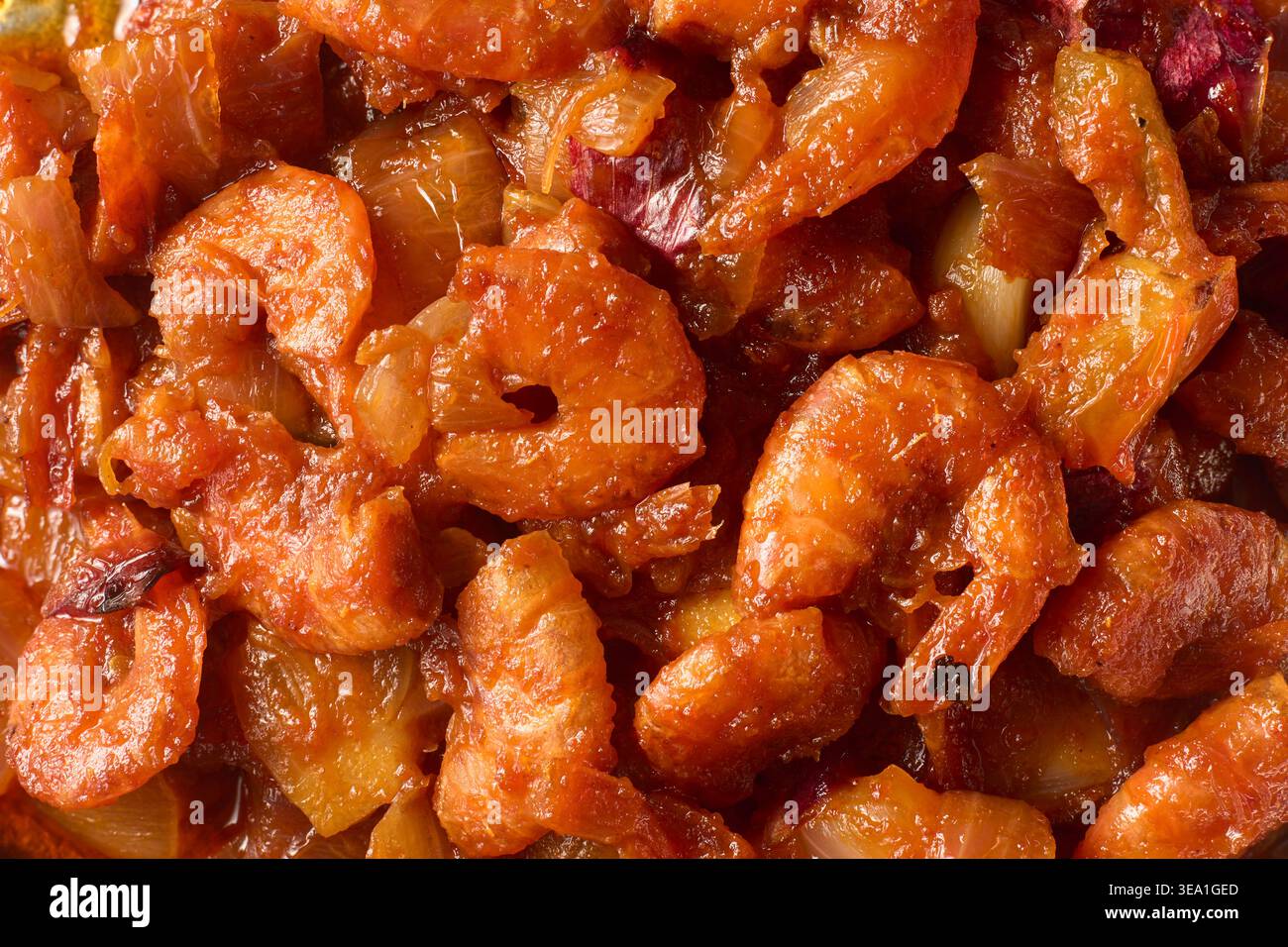 Gekochte Garnelen in scharfer roter Sauce mit gehackten Zwiebeln im Vollformat, Nahaufnahme von Garnelen in dicker herzhafter Soße, kulinarisches Meeresfrüchte-Hintergrundkonzept Stockfoto
