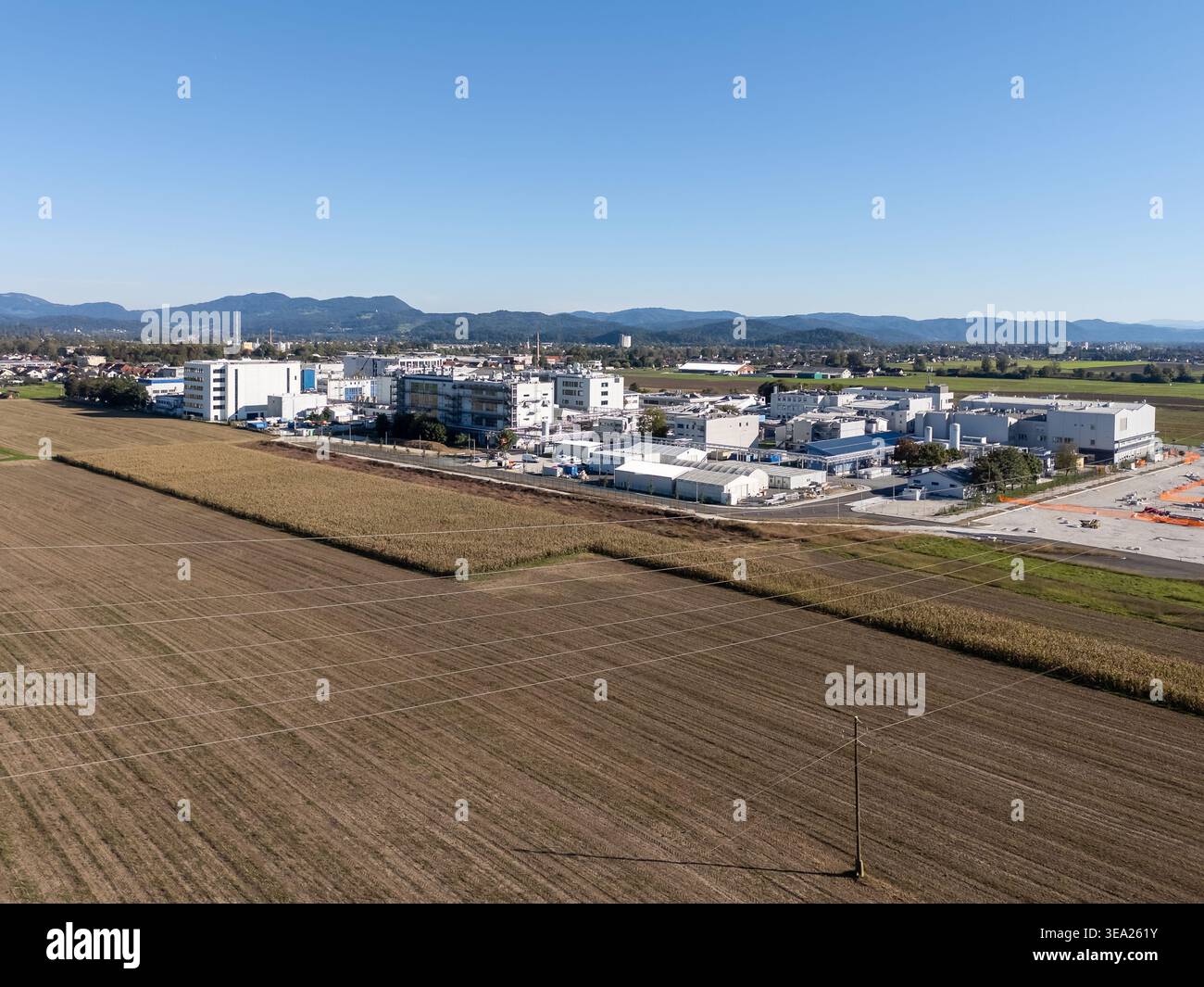 Aus der Vogelperspektive sehen Sie eine Pharmafabrik umgeben von Feldern und eine kleine Stadt. Produktionseinheiten sind Teil des Industriekomplexes. Stockfoto