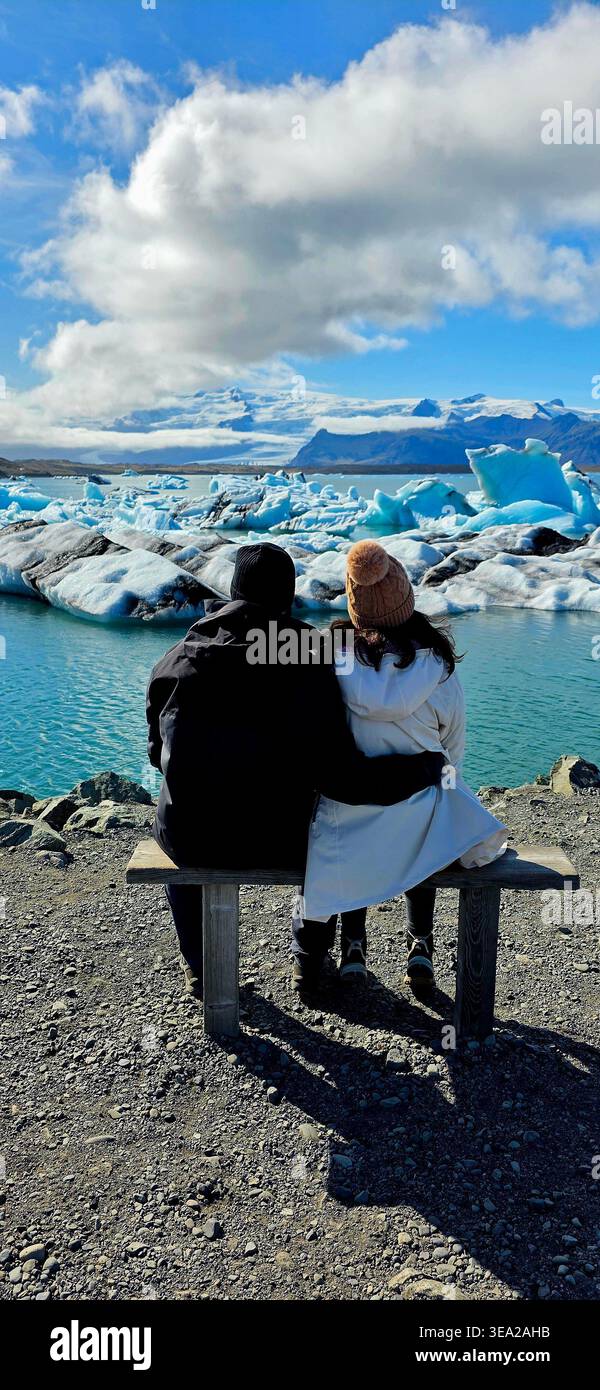 Ein Paar sitzt auf einer Bank und beobachtet den Gletscher in Island - Smartphone-aufgenommenes Stockfoto