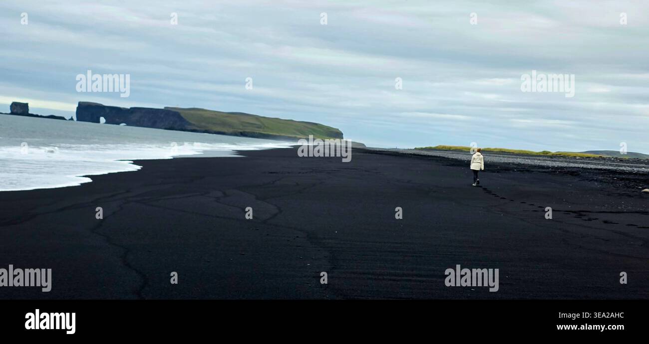 Frau mit weißer Jacke, die am Black Beach Reynisfyara läuft - Smartphone-aufgenommenes Stockfoto