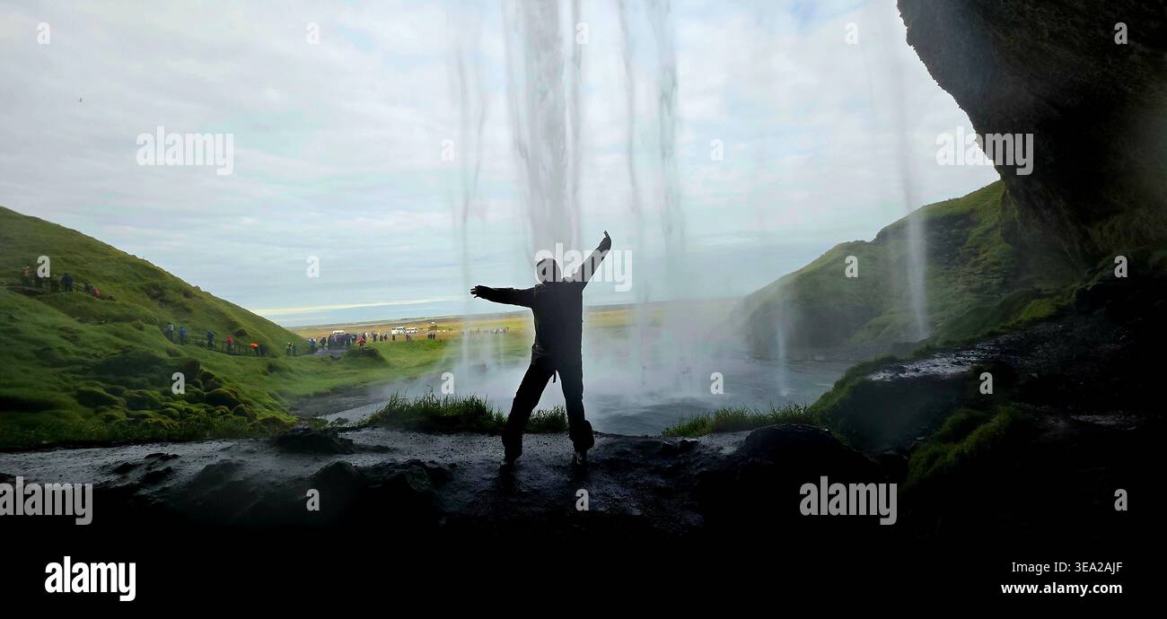 Frau, die hinter Seljalandsfoss in Island steht - Smartphone-aufgenommenes Stockfoto