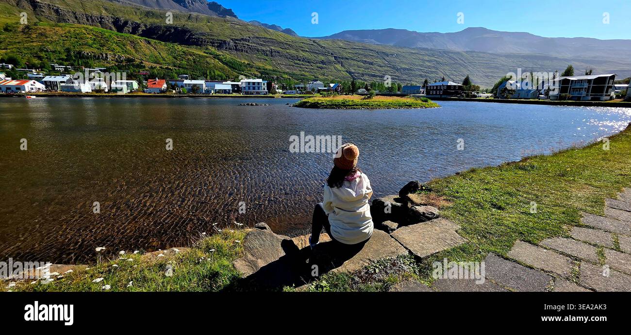 Frau, die den See in Seydisfjordur beobachtet - Smartphone-aufgenommenes Stockfoto