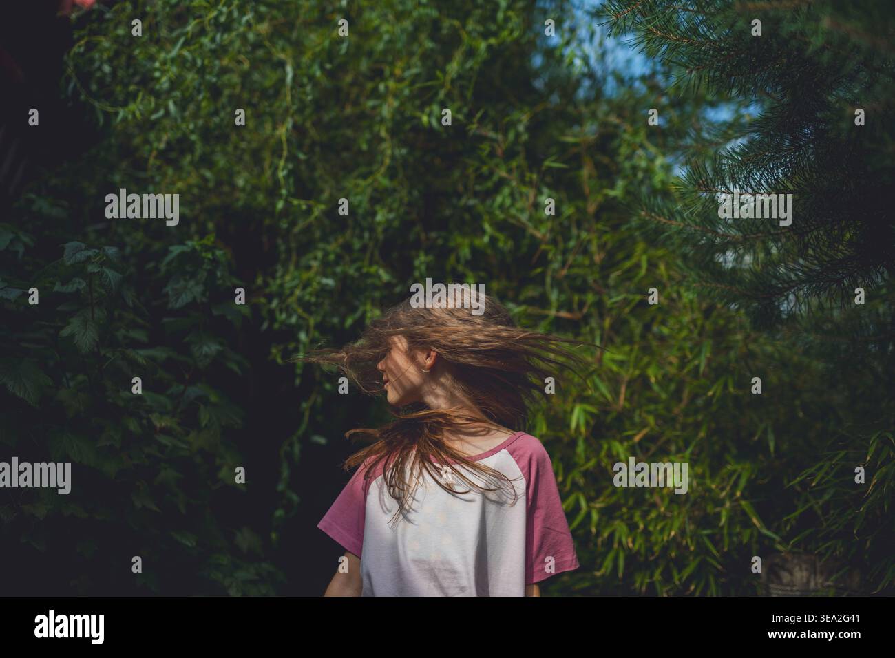 Sorgloses Mädchen, das sich im Garten während des warmen Sommertages dreht. Stockfoto