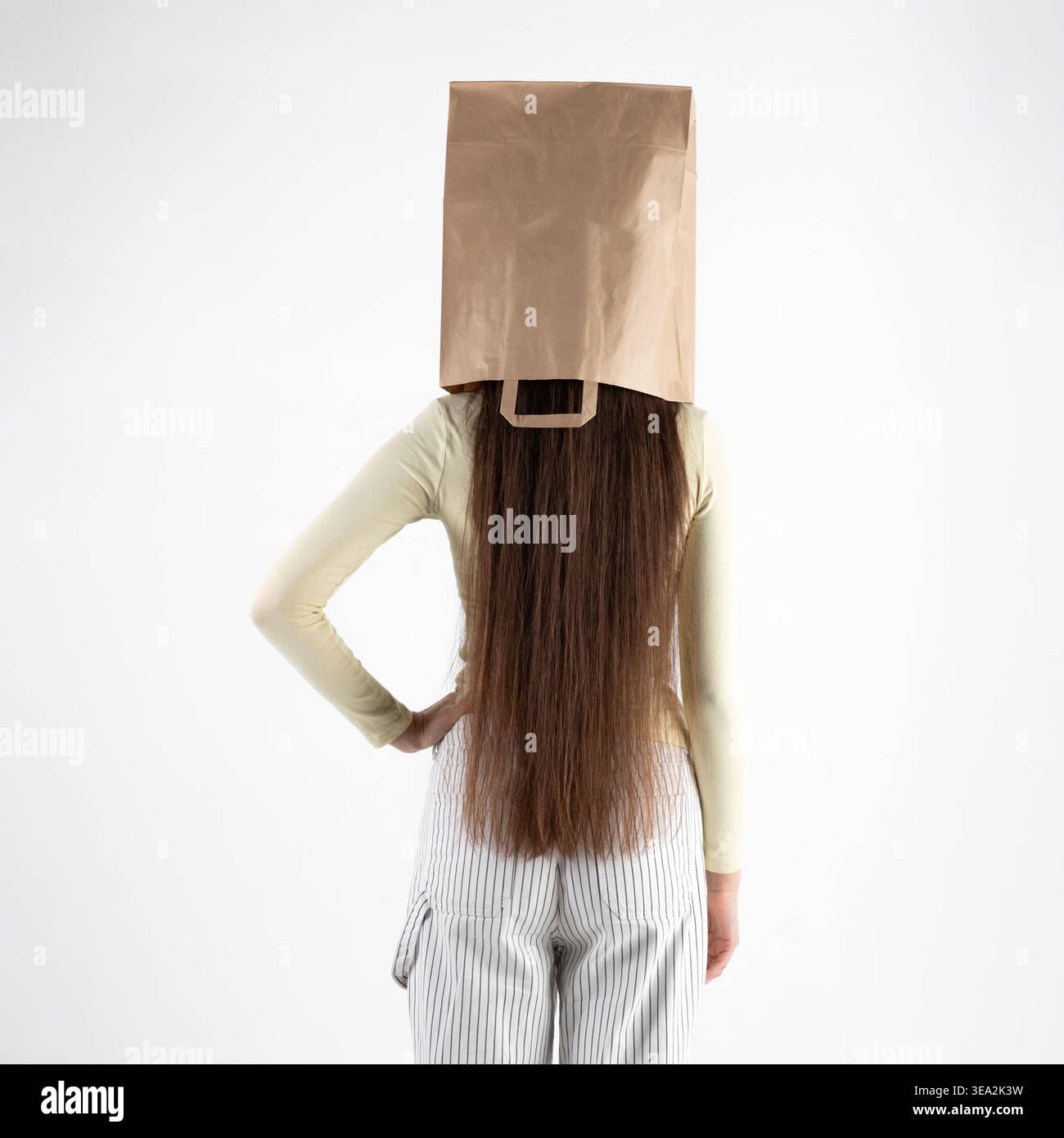 Eine Person, die mit einer braunen Papiertüte über dem Kopf steht, symbolisiert Anonymität und versteckte Identität Stockfoto