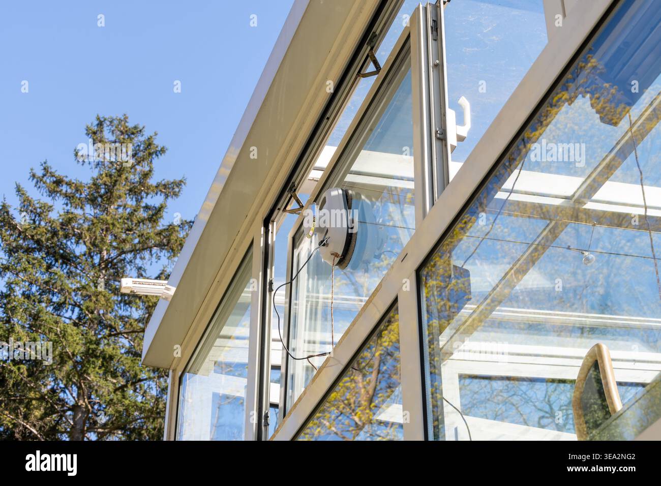 Der Fensterroboter reinigt an sonnigen Tagen die Fassade von Glasgebäuden im Freien. Stockfoto