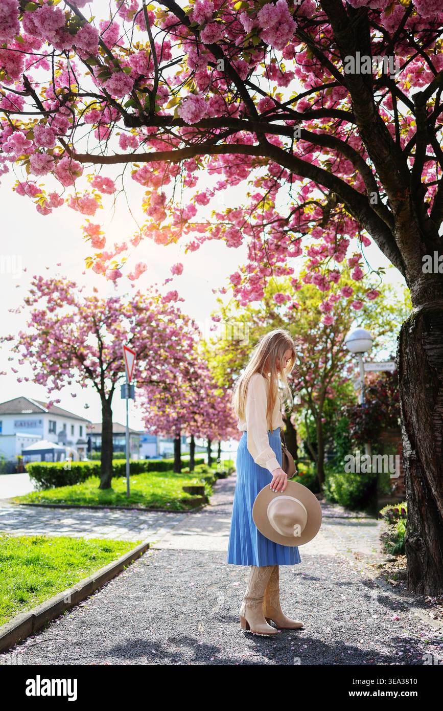 Frau im Park unter Kirschblüten, lebhafter Frühlingsszene und Inspiration für Reisen. Stockfoto