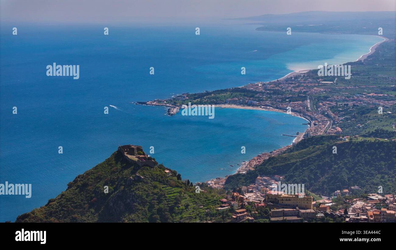 Blick aus der Vogelperspektive auf das Sarazenschloss auf einem Hügel mit Blick auf das türkisfarbene Wasser der Bucht von Giardini Naxos und die gekrümmte Küste von Taormina, Sizilien Stockfoto