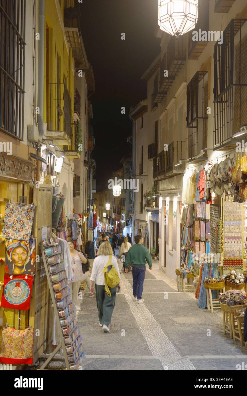 Touristen, die nachts durch den Basar von Alcaicería schlendern, gesäumt von bunten Souvenirläden und maurischem Kunsthandwerk in Granadas historischem Viertel, Spanien Stockfoto