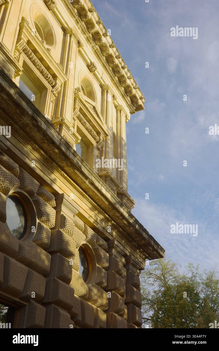 Flacher Blick auf die Fassade des Palastes von Karl V. mit rustikalem Steinwerk, geschnitzten Reliefs und bogenförmigen Fenstern im goldenen Sonnenlicht, Alhambra, Granada Stockfoto