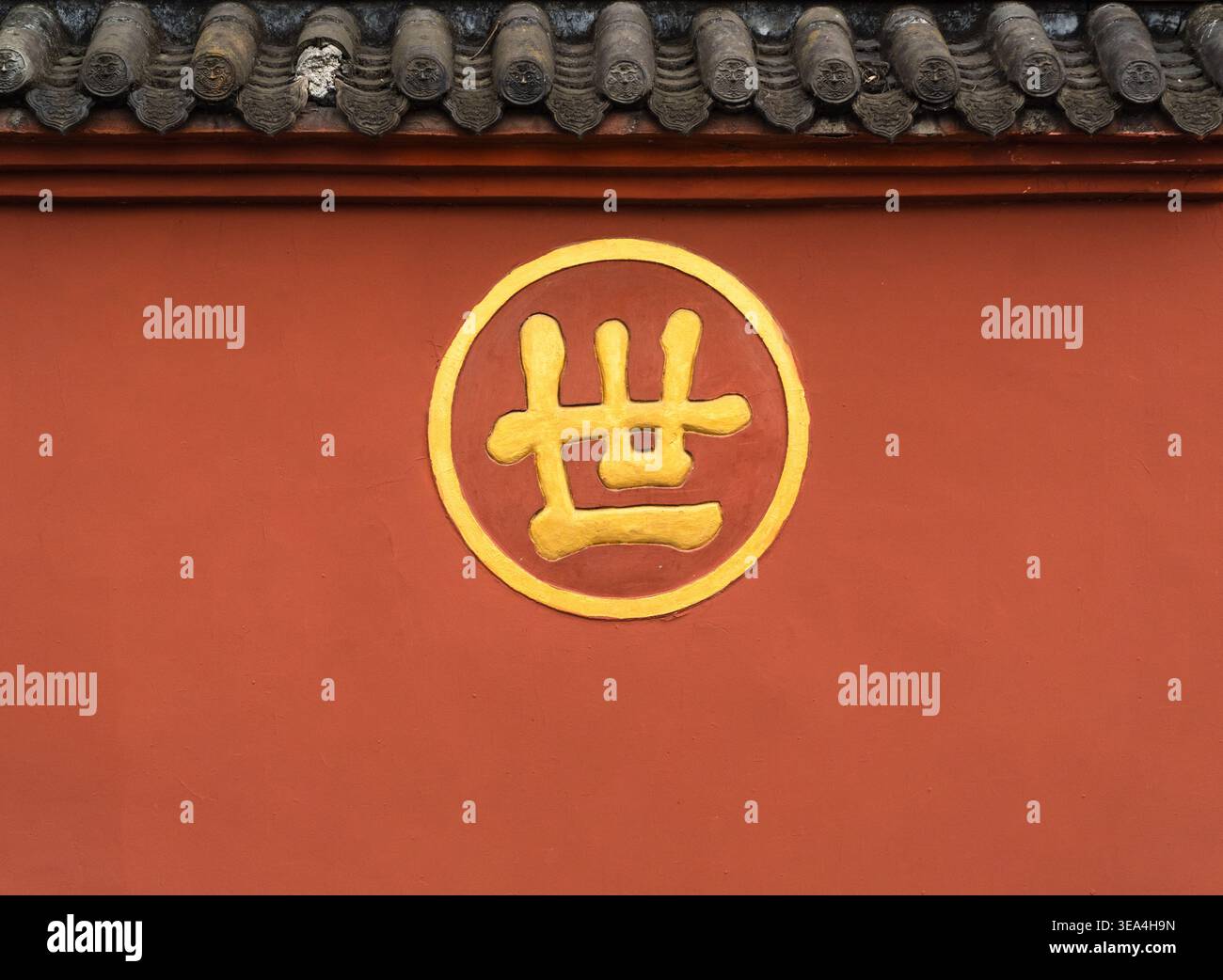 Nahaufnahme einer traditionellen roten Tempelwand mit goldenem chinesischem Charakter und grauen Dachziegeln in Chengdu. Stockfoto