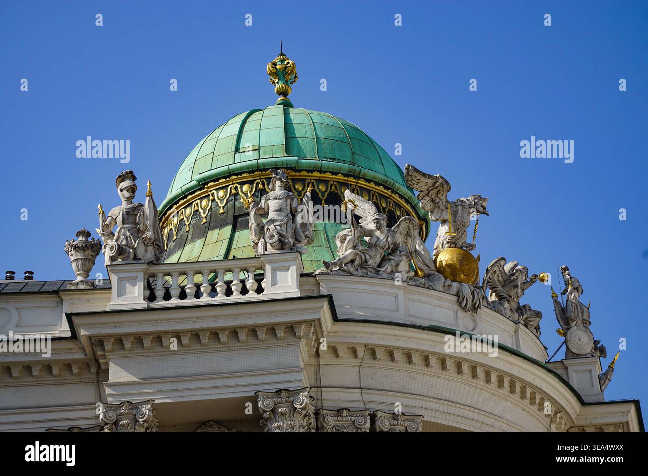 Barocke architektonische Kuppel mit Skulpturen und vergoldeten Details auf dem historischen Gebäudedach vor klarem blauem Himmel in Wien, Österreich. Stockfoto