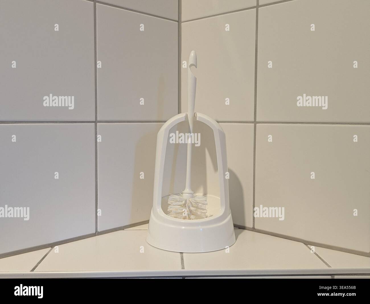 Ein sauberer Schuss von einem einfachen Toilettenbürstenset auf einem Keramikboden im Badezimmer. Unverzichtbares Werkzeug für die Hausreinigung, die allgemeine Ordnung und Sauberkeit Stockfoto