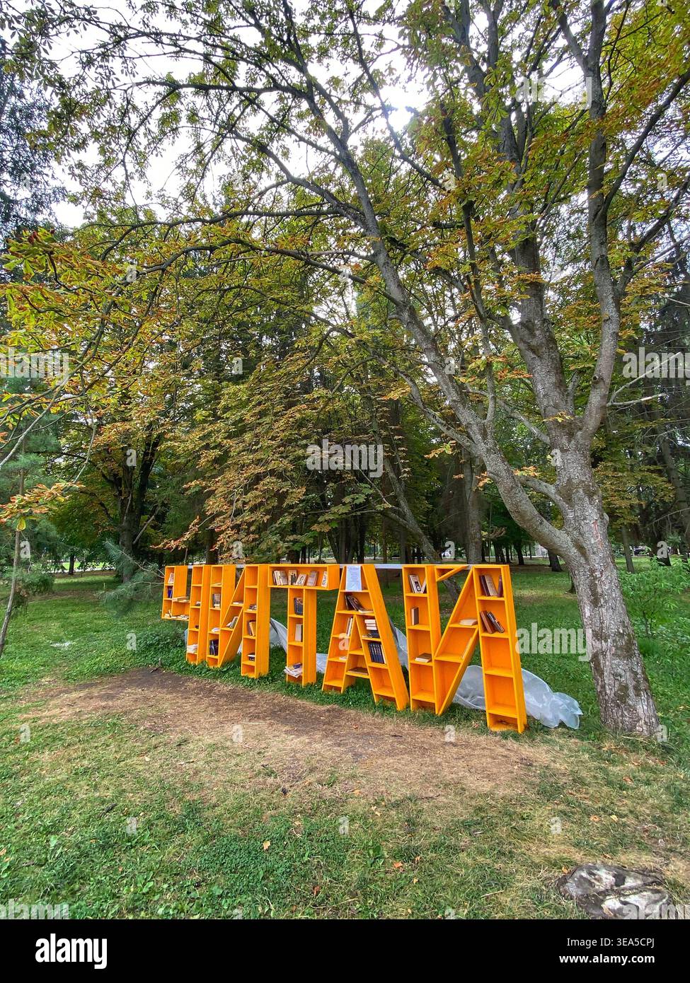 Belgorod, Russland – 8. August 2021: Öffentliche Buchinstallation im Freien in einem Park mit großen orangen Buchregalen in Form von Buchstaben zwischen Bäumen Stockfoto