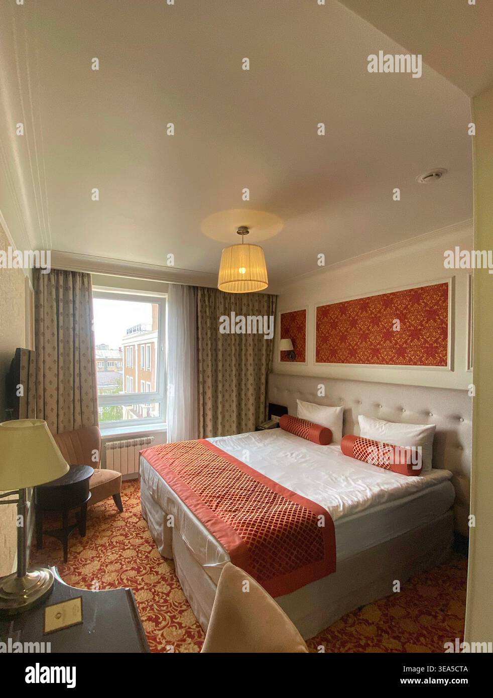 Gemütliches Hotelzimmer mit Doppelbett, warmer Beleuchtung und elegantem klassischem Design Stockfoto