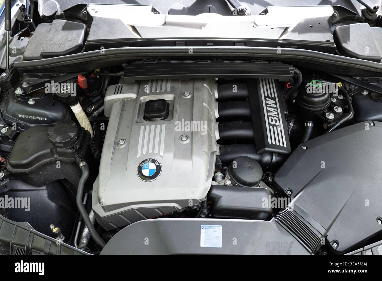 Zürich, Schweiz, 17. April 2026. Draufsicht auf einen silbernen BMW N52B30 3,0-Liter-Reihenmotor mit sechs Benzinmotoren in einem blauen Metallic-Fahrzeug Stockfoto