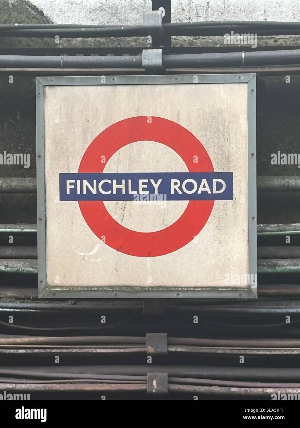 Verwitterte Finchley Road Londoner U-Bahn-Station Schild mit freiliegenden industriellen elektrischen Kabeln - Smartphone-aufgenommenes Stockfoto