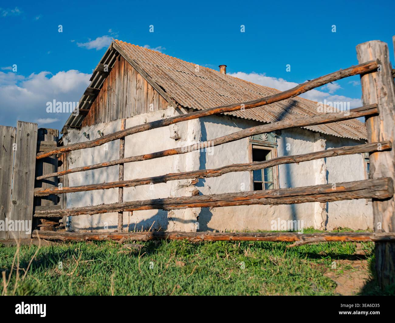Altes Bauernhaus mit Holzzaun in ländlicher Gegend unter blauem Himmel bei Tageslicht Stockfoto