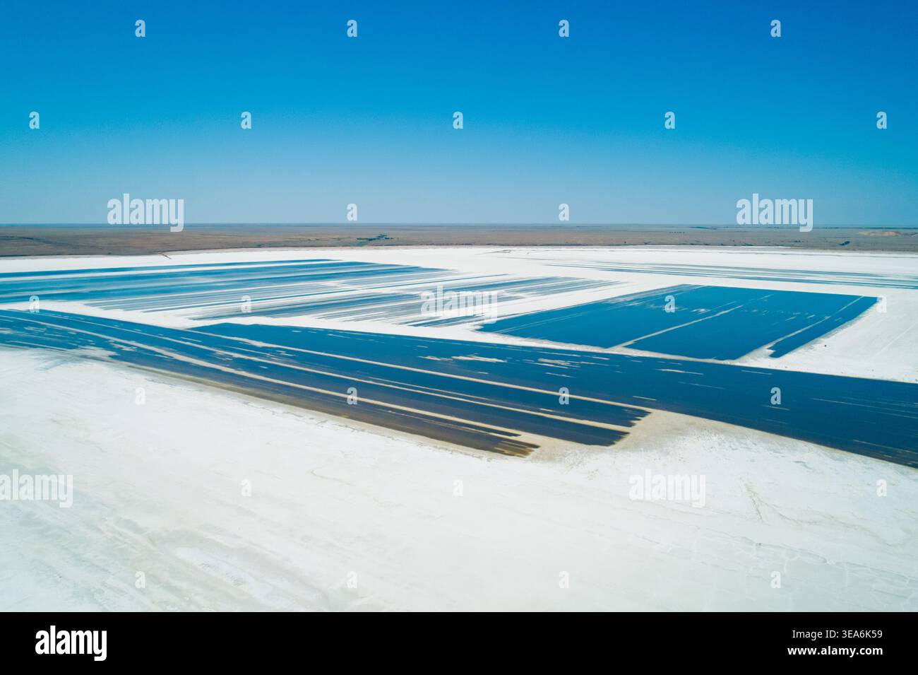 Salzverdunstungsteiche am Baskunchak Lake spiegeln den blauen Himmel wider und zeigen tagsüber riesige Mineralienabbaubetriebe Stockfoto
