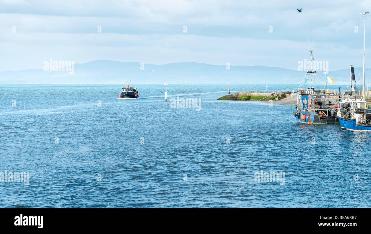 Minimalistische Küstenlandschaft mit Fischereifahrzeugen am Annagassan Village Harbour an einem hellen bewölkten Tag in Irland. Stockfoto
