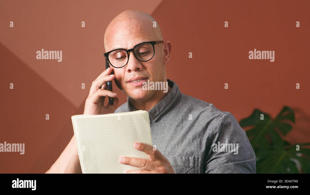 Geschäftsmann Am Telefon Überprüft Notizen In Moderner Büroumgebung Mit Fokussiertem Ausdruck Stockfoto