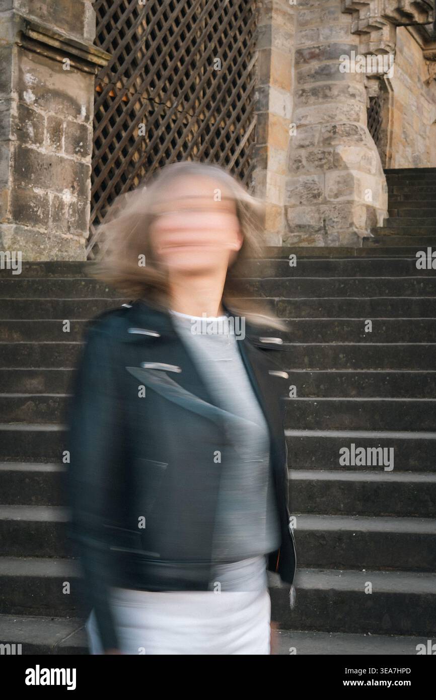 Kreatives Bewegungsunschärfe Porträt einer Frau, die auf dunklen Steintreppen in der Nähe der historischen Kathedralarchitektur steht. Urbanes Konzeptbild mit Anonymität, Mo Stockfoto