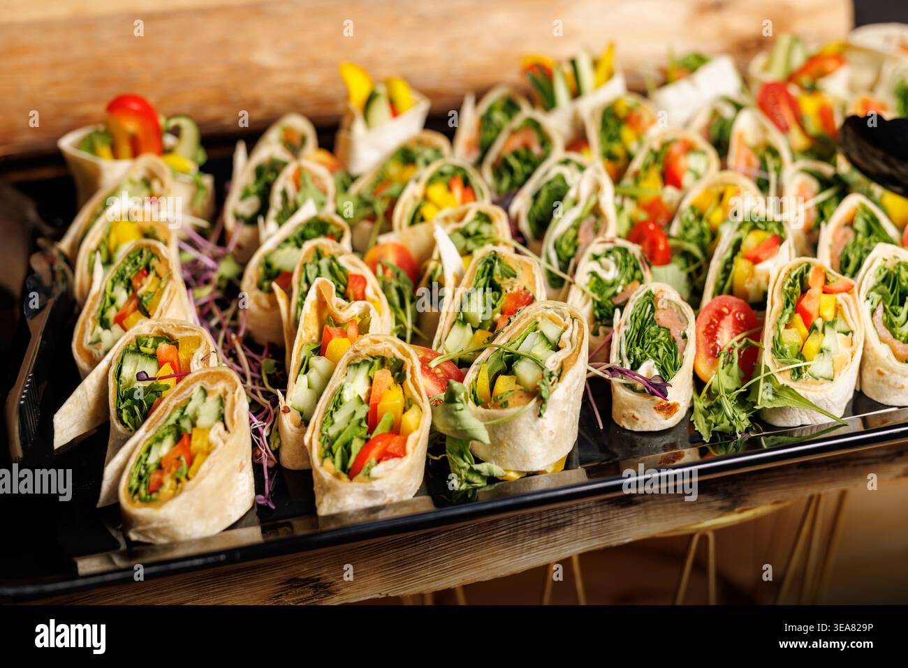 Verschiedene Gemüsetortilla-Wraps auf schwarzem Catering-Tablett Stockfoto
