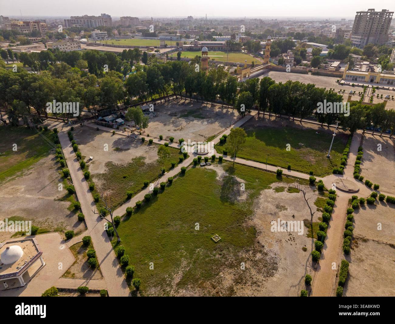 Aus der Vogelperspektive eines öffentlichen Parks mit geometrischen Wanderwegen, grünen Rasenflächen und Baumreihen unter klarem Himmel in Hyderabad, Sindh, Pakistan. Stockfoto