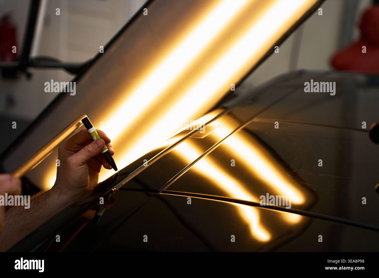 Der PDR-Techniker verwendet einen Präzisions-Niederschlagdorn und einen Holzhammer, um hohe Metallstellen zu ebnen Stockfoto