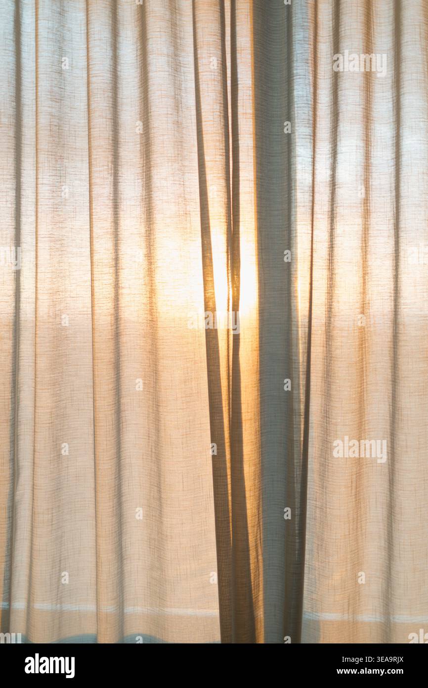 Transparente Vorhänge lassen weiches Sonnenlicht sanft durchdringen. Sanftes goldenes Licht schafft eine warme, ruhige Atmosphäre. Ideal für Morgen- oder Abendszenen. Anzeige Stockfoto