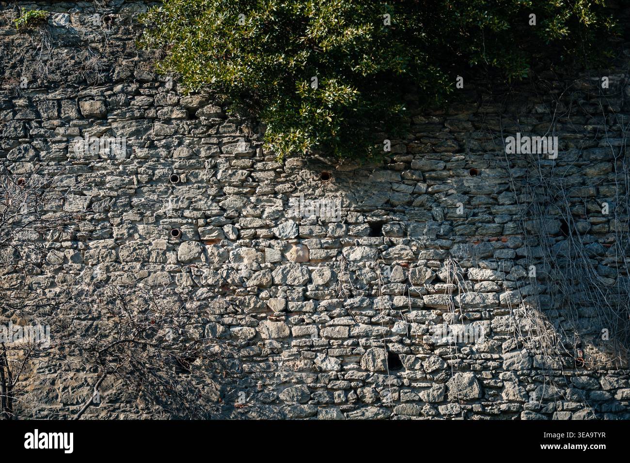 Antike Mauerwerk-Kulisse. Sonnendurchfluteter Stein Mit Strukturierter Oberfläche Und Natürlichen Flicken Stockfoto
