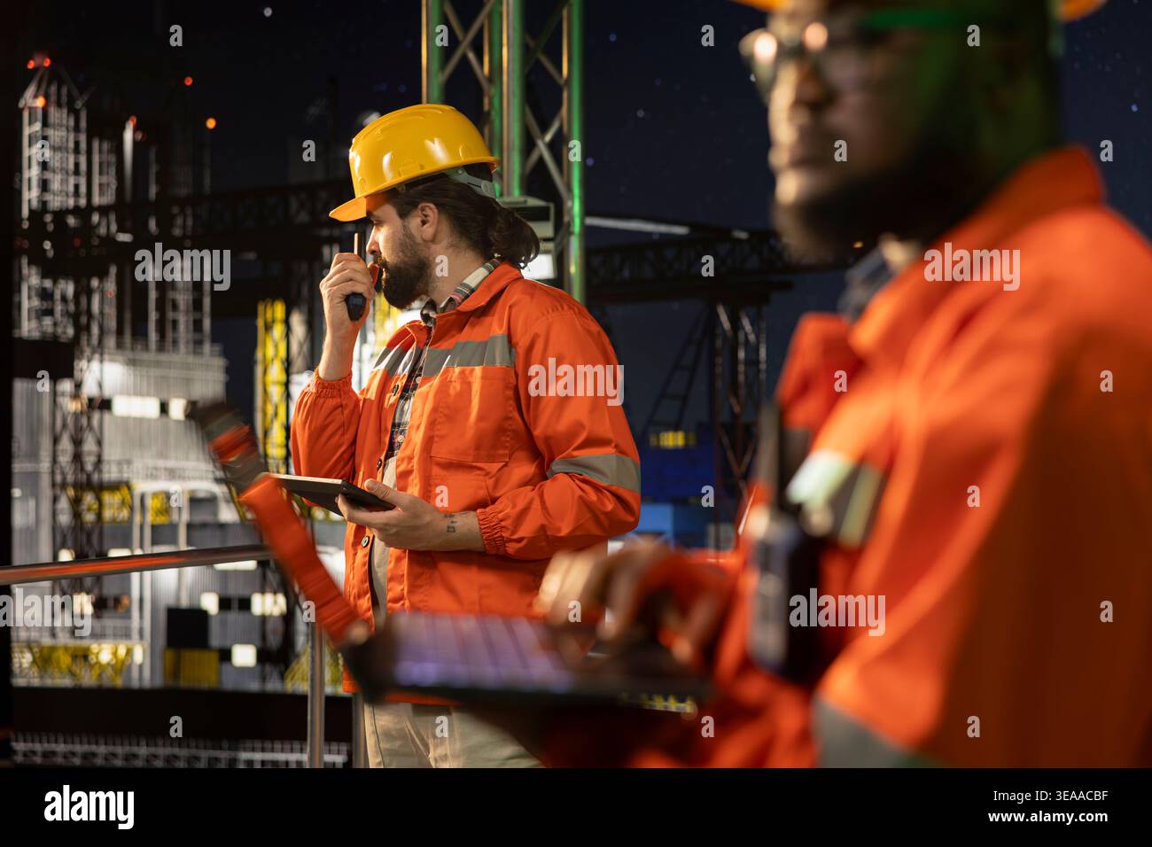 Offshore-Ölförderplattformteam mit Laptop, um Unterwassersysteme spät in der Nacht zu steuern. Experten, die gemeinsam die Erkennung von Anomalien mithilfe eines Notizbuchs beim Bohren von Derrick überwachen Stockfoto