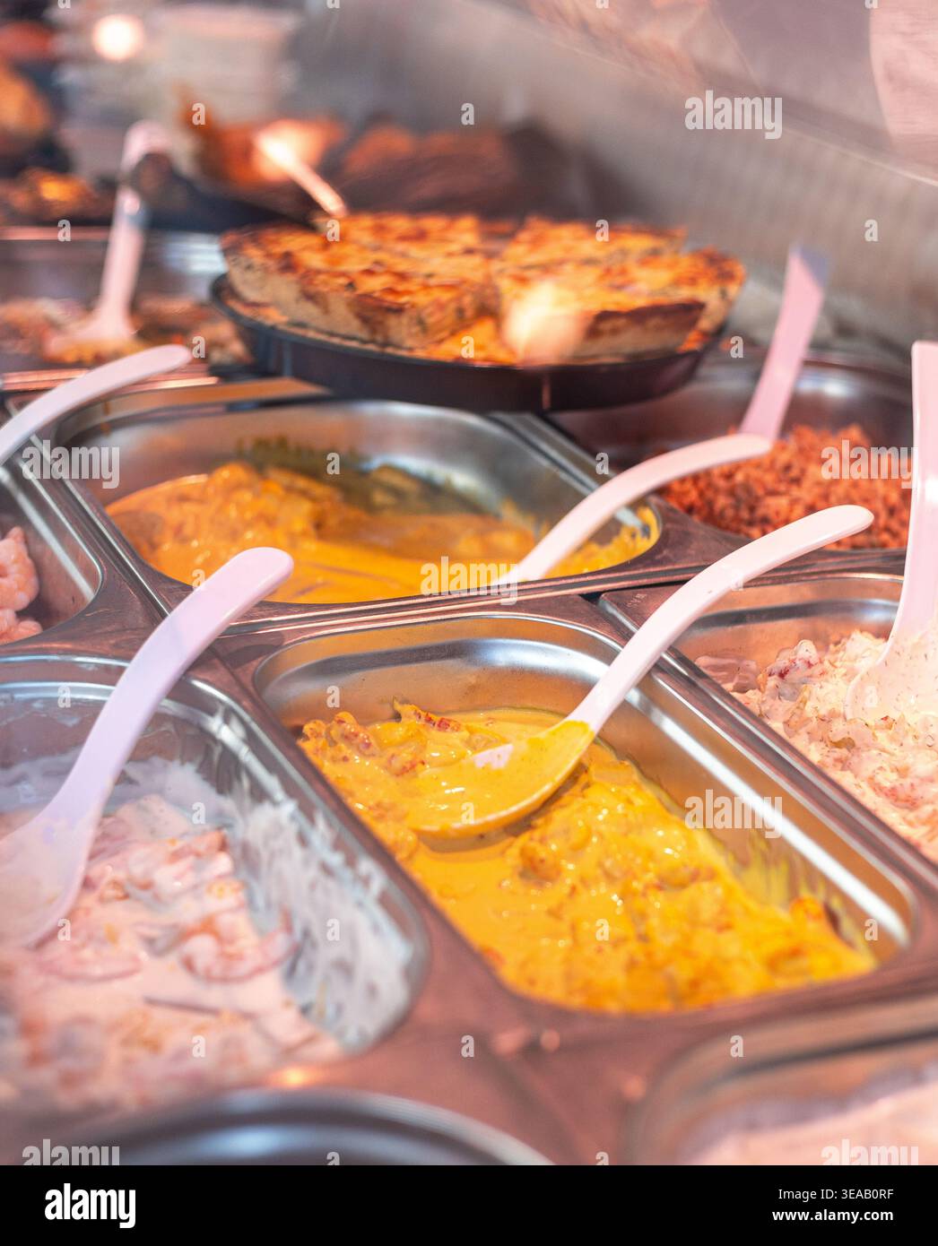 Auf einem Markt werden die Speisen in Tabletts mit einer Vielzahl von Gerichten serviert. Man kann die Leute bei der Auswahl von Speisen beobachten, während man die nachmittags-Atmosphäre genießt. Stockfoto