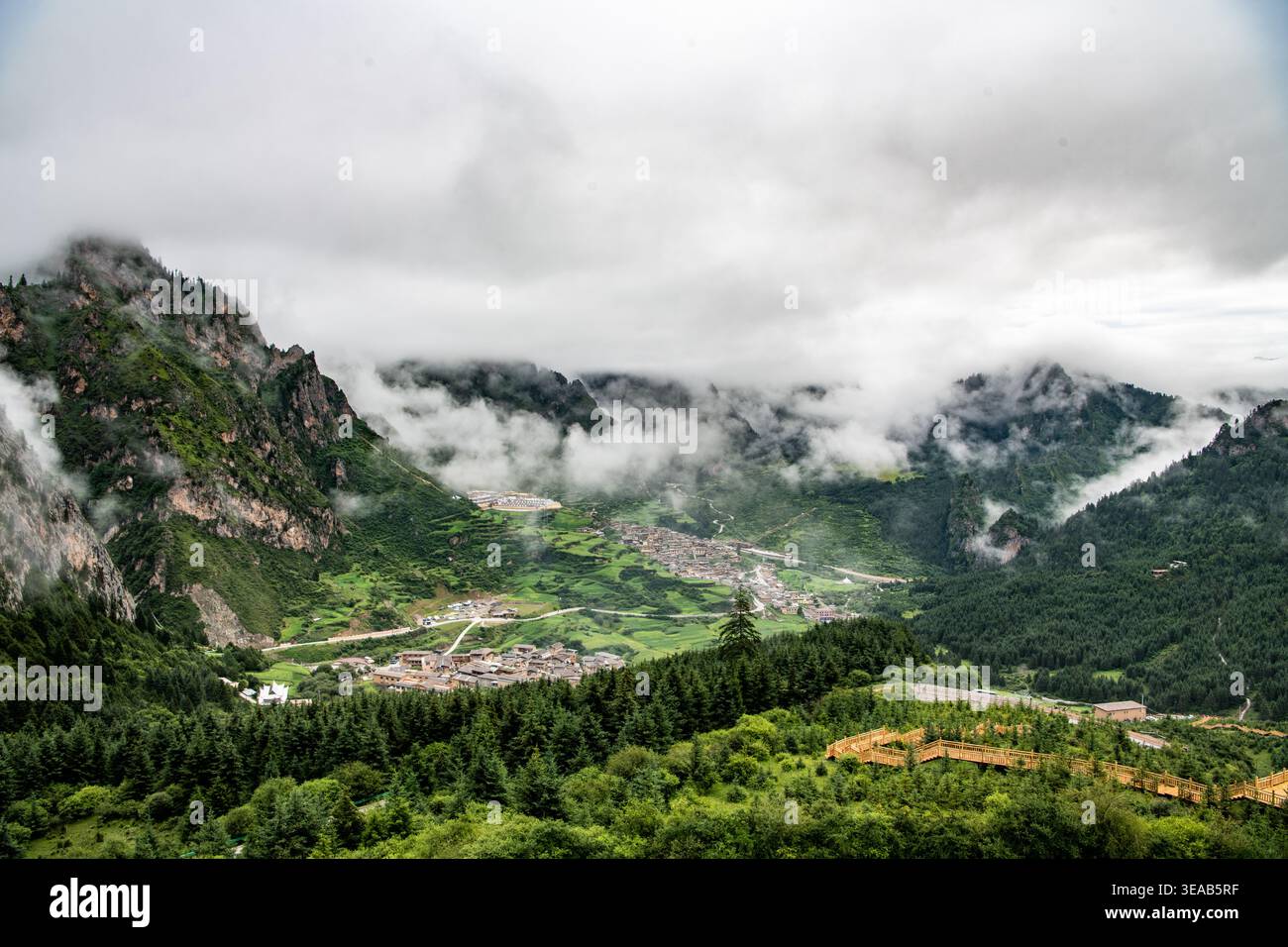 Neblige Berglandschaften von Zhagana in Gansu, China, mit dramatischen Wolken, alpinen Dörfern und zerklüfteten Gipfeln, die durch Nebel auftauchen. Stockfoto