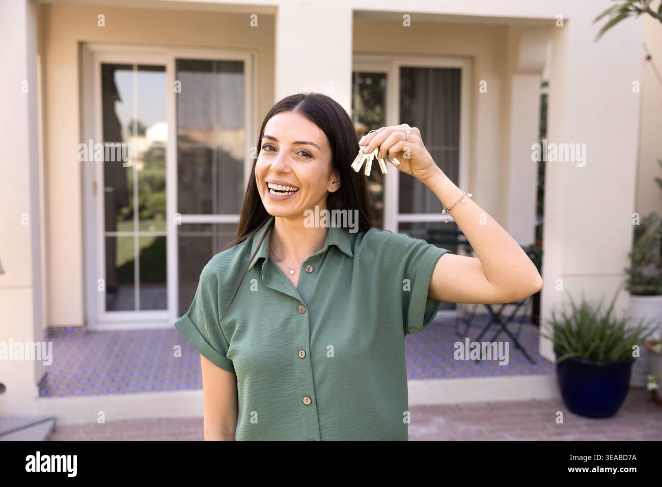 Frau, die Schlüsselsätze zeigt, steht vor dem neuen Haus Stockfoto