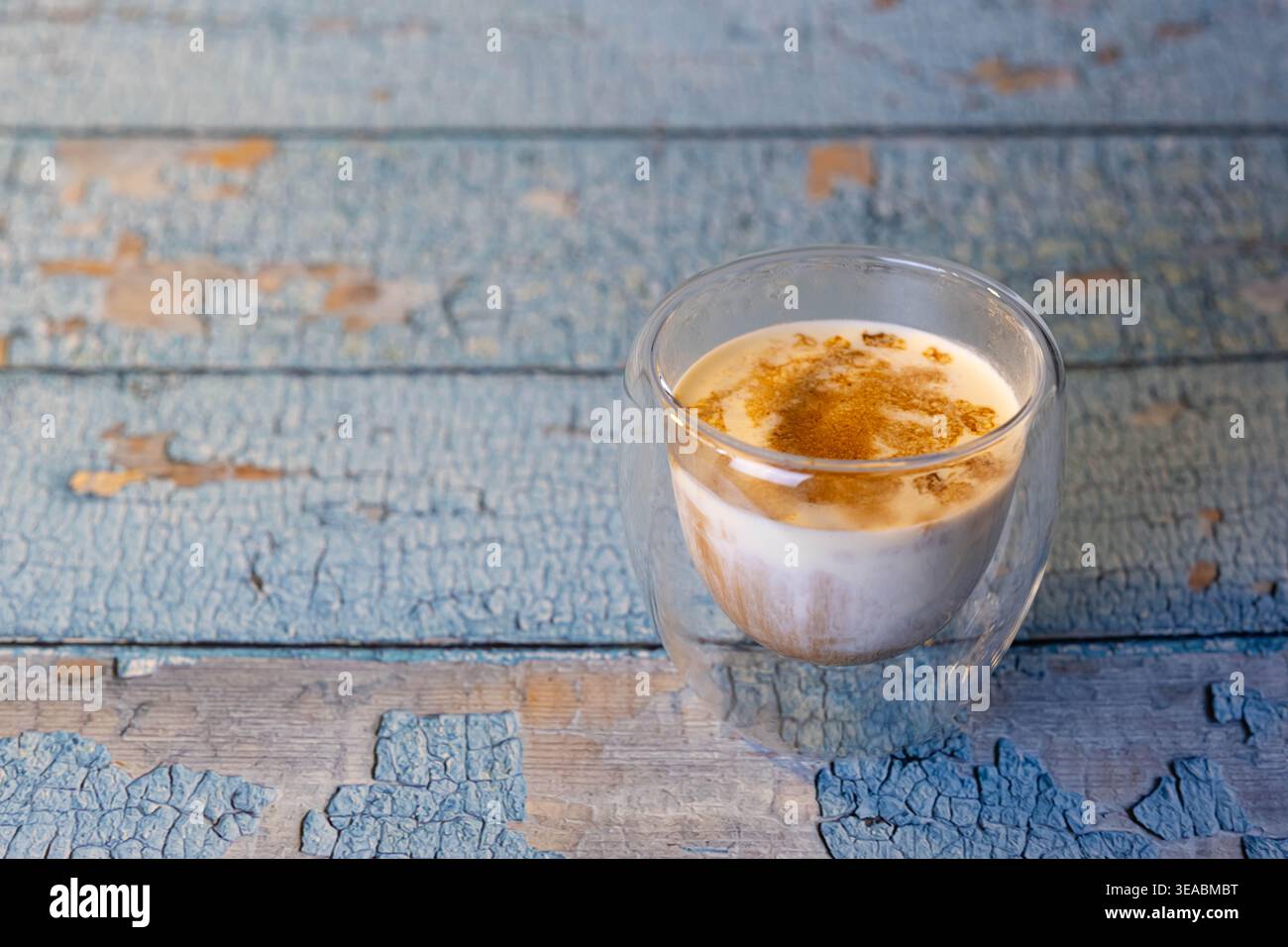 Blick von oben auf dreckigen Kaffee in doppelwandigen Glas auf rustikalem blauen Holztisch. Morning Hygge Routine mit Kopierraum für Design. Stockfoto