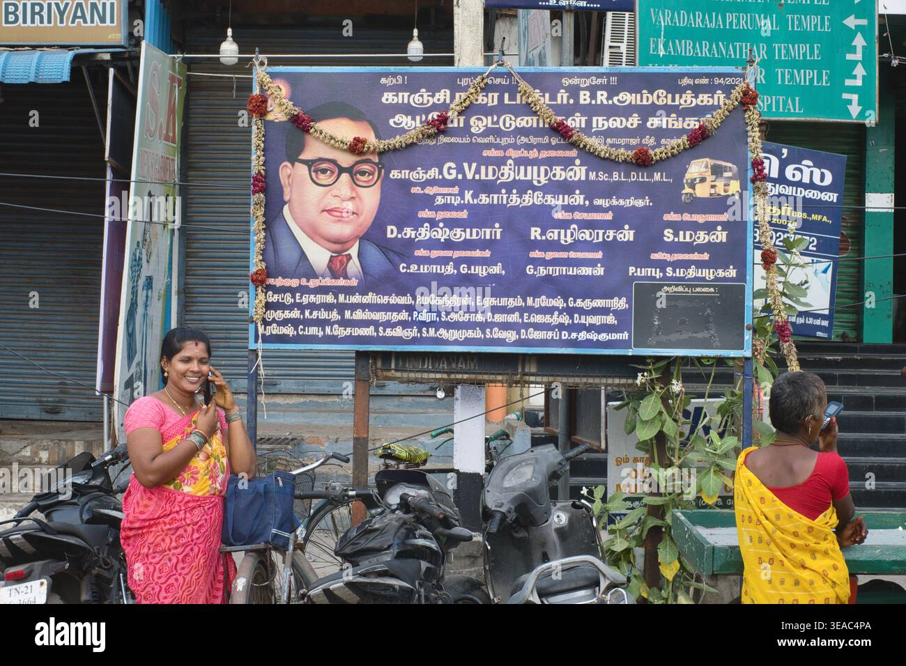 Zwei tamilische Frauen stehen neben einem Porträt von B.R. Ambedkar, indischer Reformer und Begründerin einer neo-buddhistischen Bewegung; Kanchipuram, Tamil Nadu, S.India Stockfoto