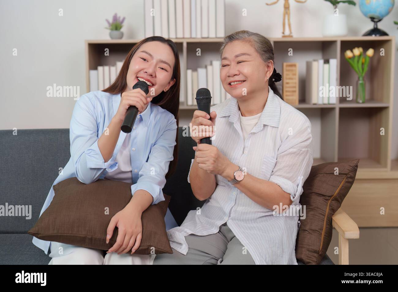 Asiatische Mutter und Tochter singen Karaoke und haben zu Hause Spaß Stockfoto