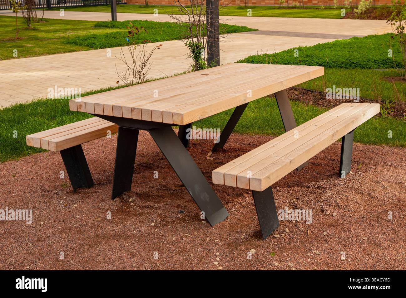 Picknicktisch im Freien für 6 Personen aus Douglasie. Ein hölzerner Picknicktisch mit schwarzen Metallbeinen steht auf Kies in einem gepflegten Garten Stockfoto