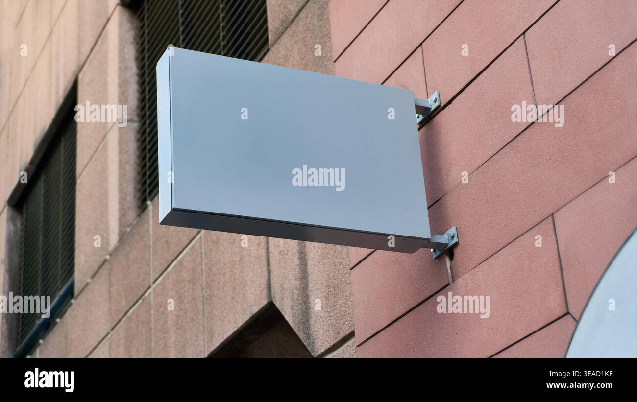Für Werbemockup-Vorlagen, die leere Schilderflächen für Markenwerbung und Verkaufsmöglichkeiten zeigen, ist ein leeres Ladenfront-Schild an einer Gebäudeaußenfläche angebracht, die städtischen Gewerbeflächen bietet. Stockfoto