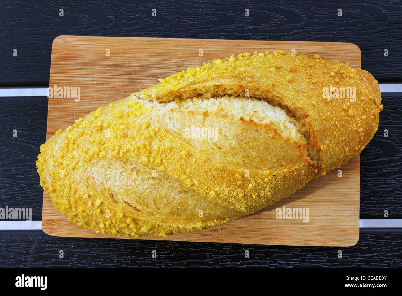 Blick von oben auf einen kroatischen Maisbrotlaib, der auf einem Holzschneidebrett auf einem dunklen Lattentisch steht. Selektiver Fokus Stockfoto