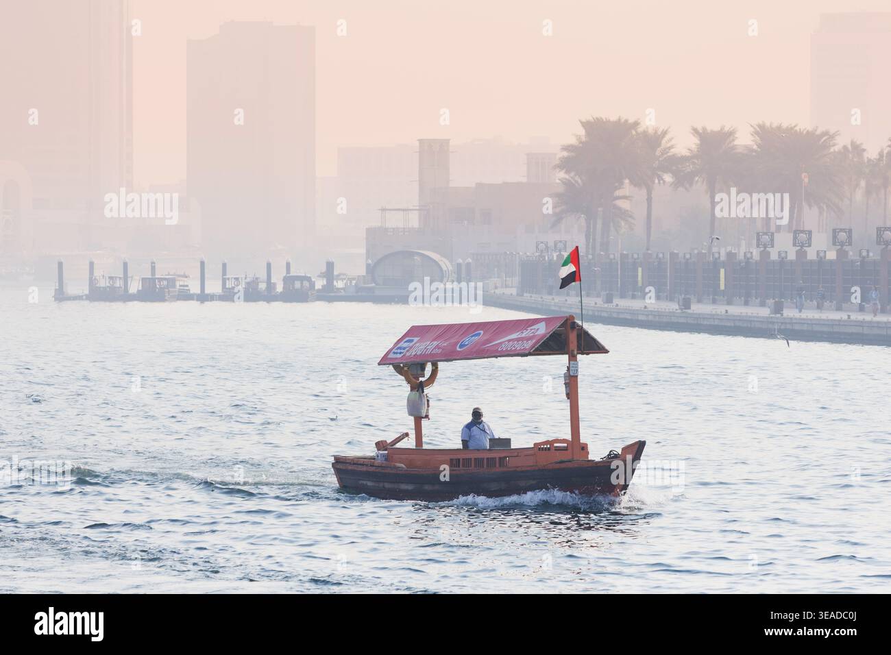 12. Januar 2026, Dubai, VAE: Traditionelle Abra-Boote transportieren Passagiere über den Dubai Creek und verbinden alte und neue Teile der Stadt mit einem trüben Skyl Stockfoto