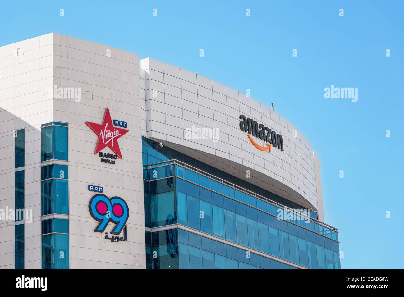 14. Januar 2026, Dubai, Vereinigte Arabische Emirate: Logos bekannter internationaler Unternehmen Amazon, Virgin Radio Dubai und ARN 99 auf einer modernen Fassade eines Bürogebäudes Stockfoto