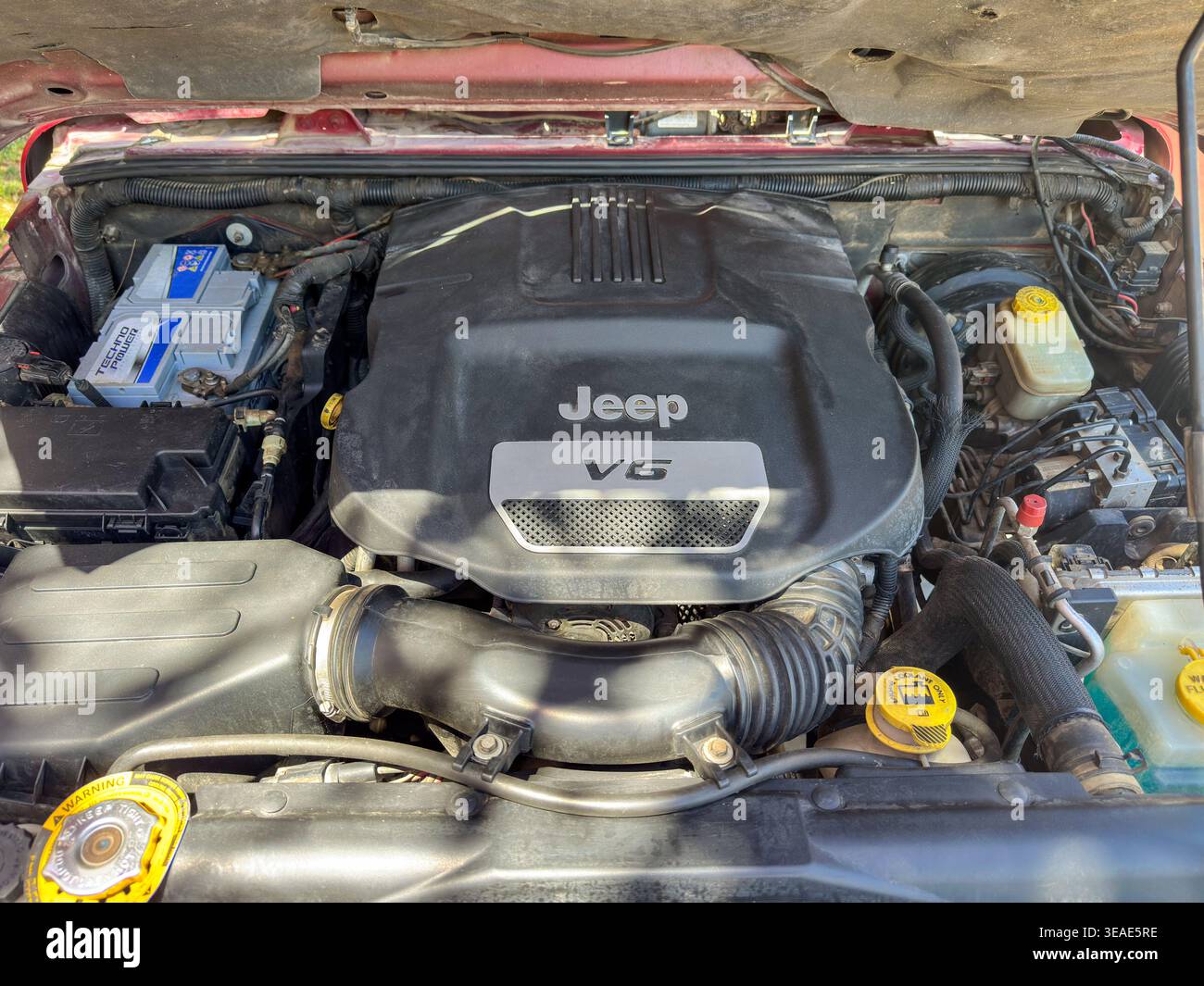 Jeep Wrangler JK V6 Motorraum mit geöffneter Motorhaube, Motorhaube, Batterie und Komponenten unter der Motorhaube bei Tageslicht Stockfoto