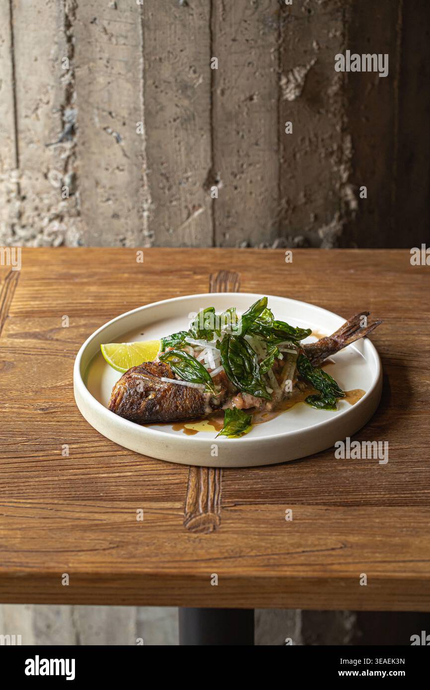Gegrillter Fisch mit Kräutern und Limette auf Teller Stockfoto