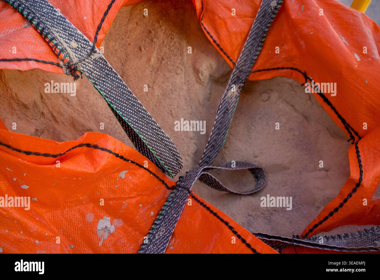 Nahaufnahme von Sand in großen industriellen Schütttüten mit Hebegurten. Baumaterial wird in robusten Beuteln für Bau- oder Renovierungsarbeiten gelagert. Stockfoto